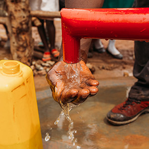 A hand catches clean water being pumped out of a well